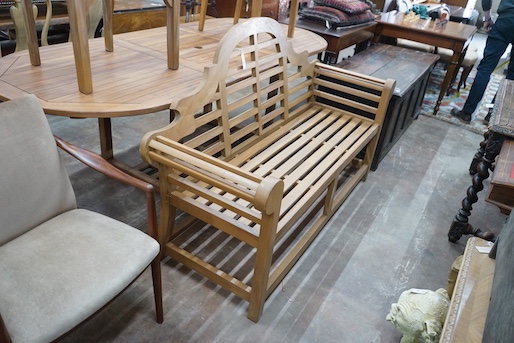 An extending teak garden table, length 140cm extended, width 100cm, height 75cm, a Lutyens style teak garden bench and two elbow chairs with waterproof covers